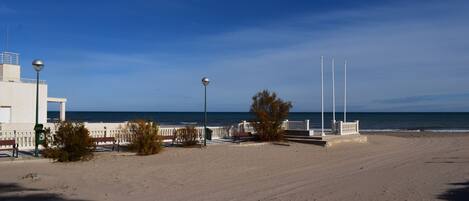 A beach with a white building, a fence, and street lamps.