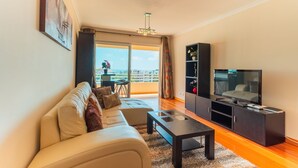 Una sala de estar moderna con sofá, una mesa de centro, televisor y un balcón con vistas.