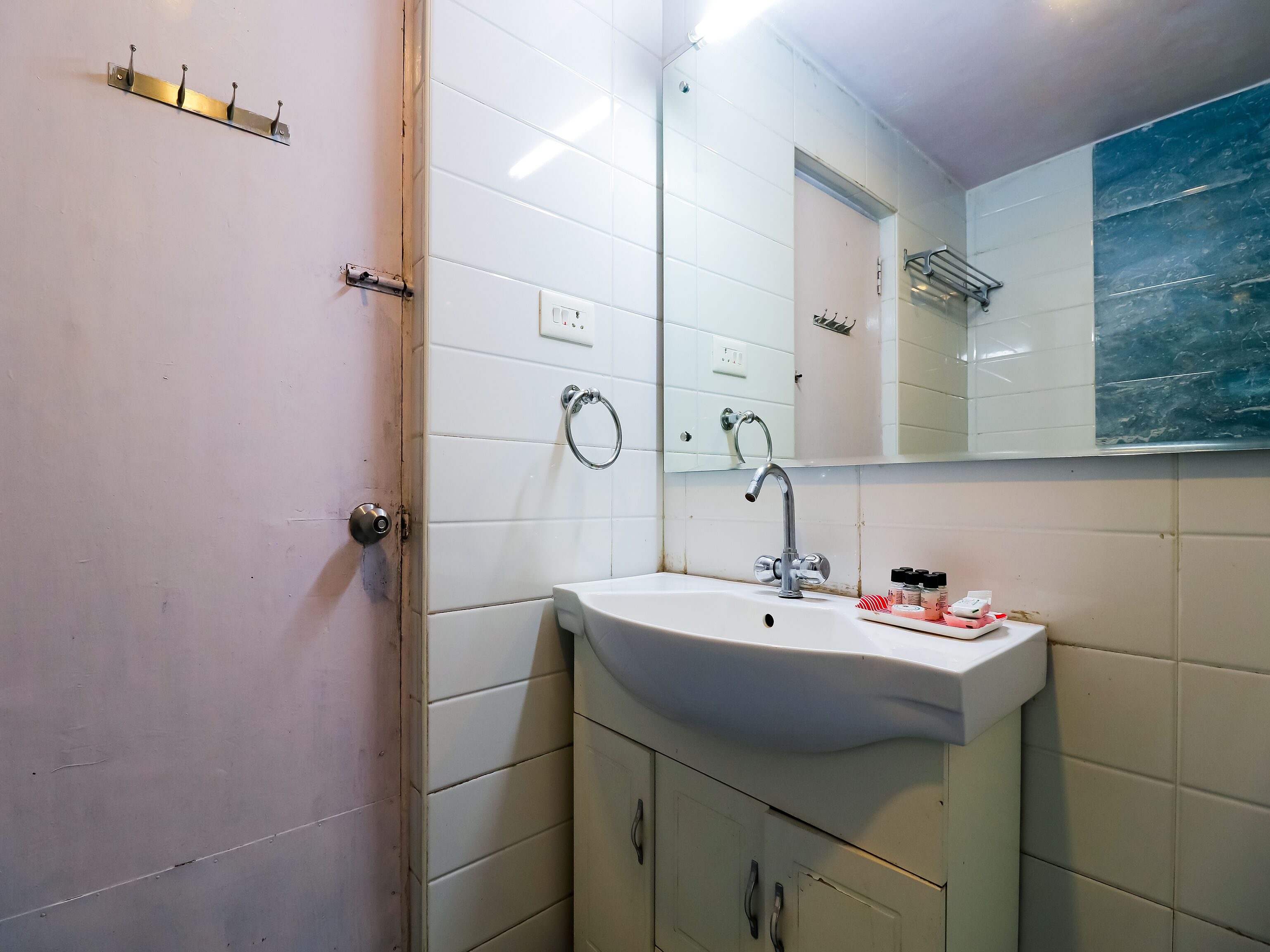 Une salle de bain avec un lavabo blanc, un miroir et un porte-serviettes.
