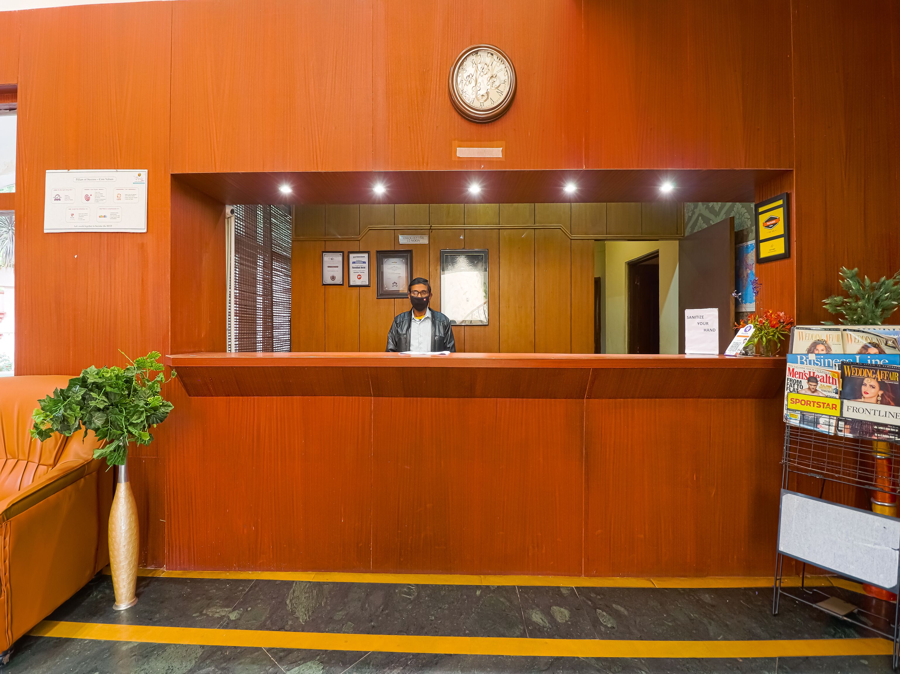 A reception desk with a clock above it, framed certificates on the wall, and a magazine rack to the right.