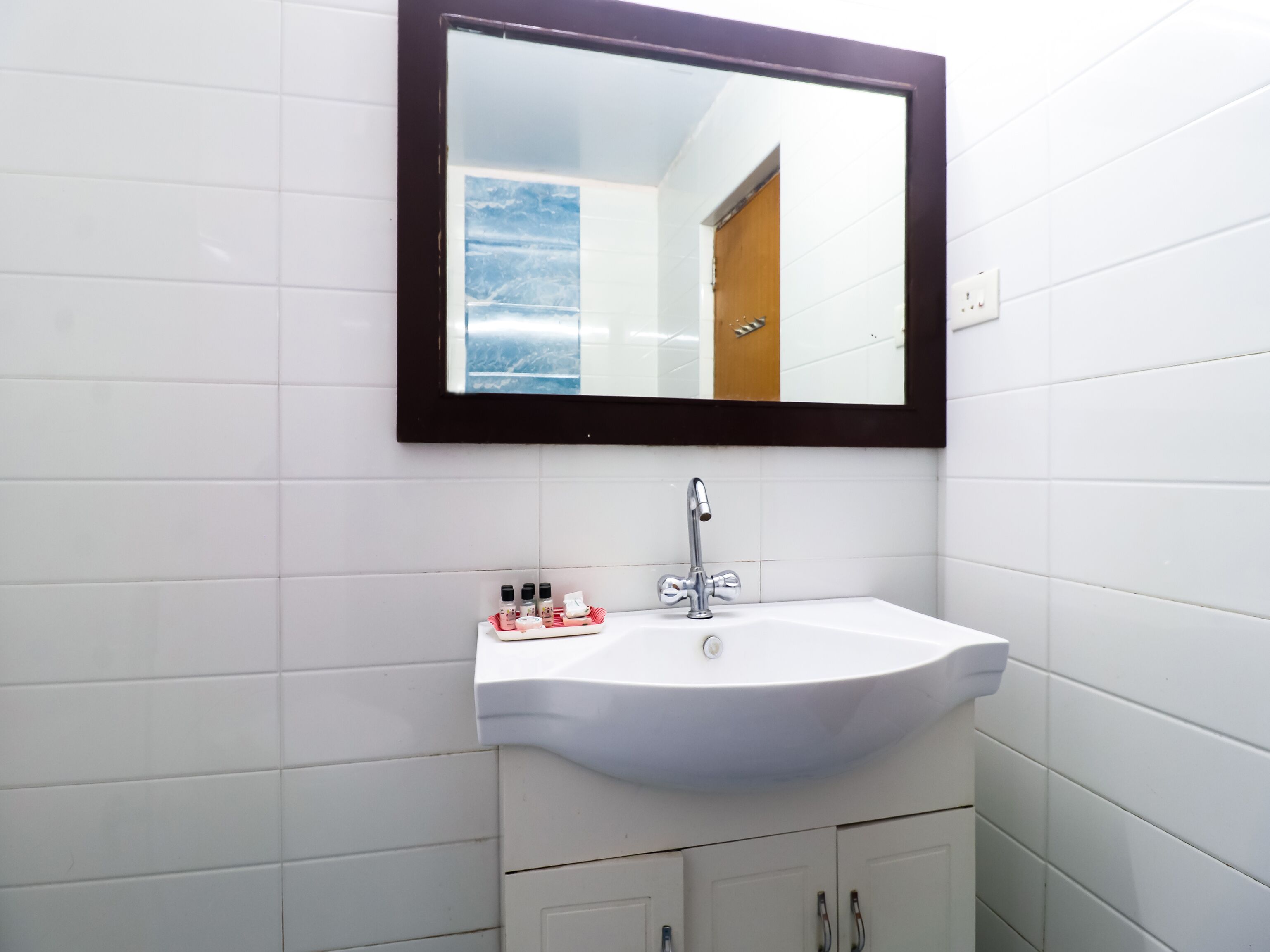 Un baño con un lavamanos blanco, un espejo y un mueble debajo.