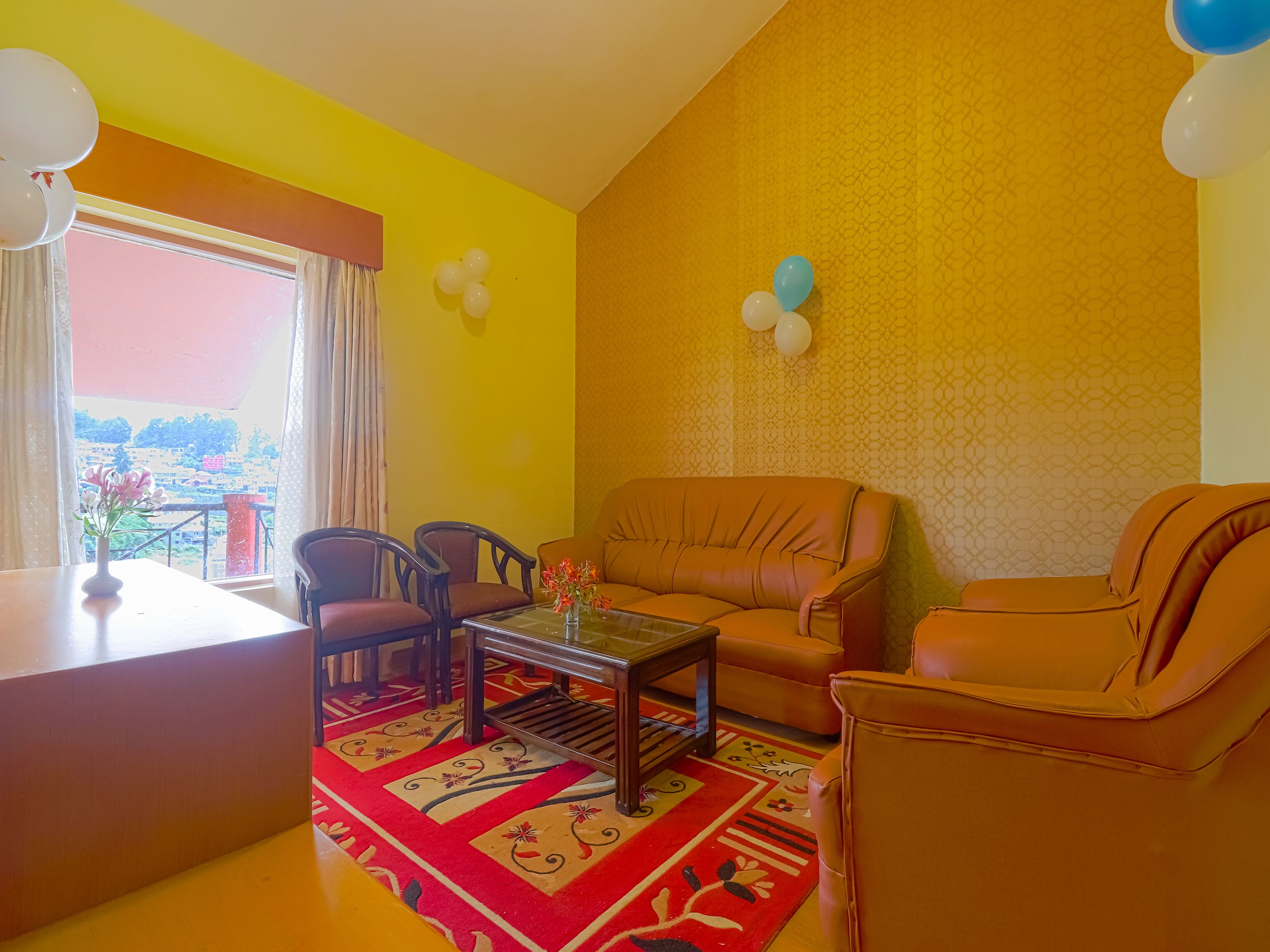 A living room with a sofa, chairs, a coffee table, and a view through a window.