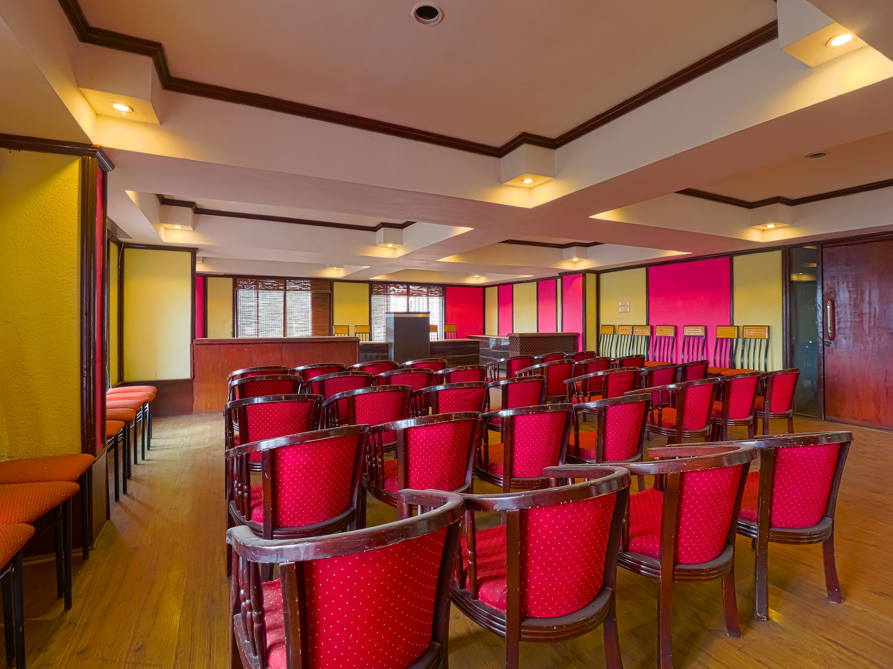 A conference room with rows of red chairs, a podium, and a stage.