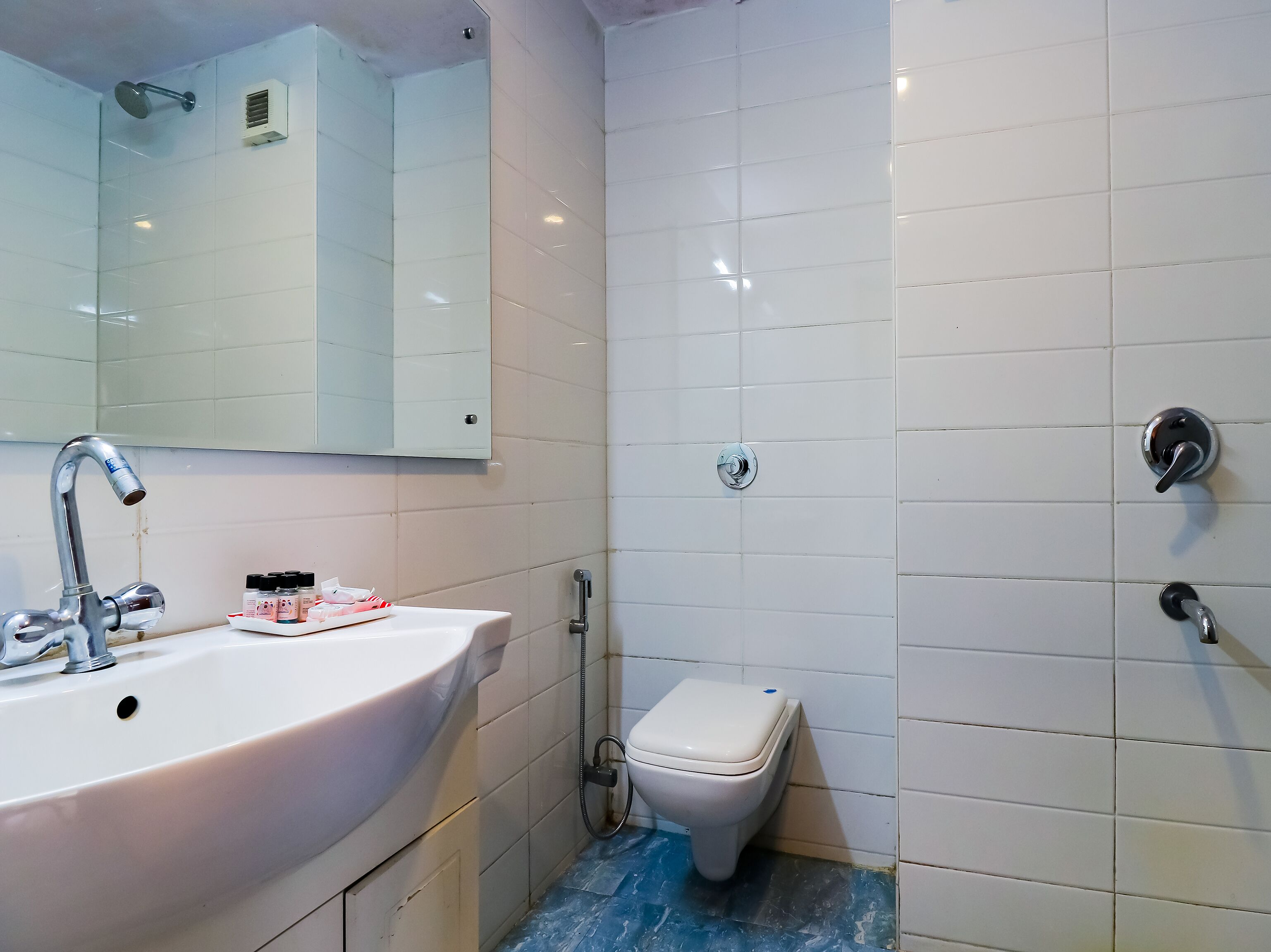 A bathroom with a white sink, a mirror, a toilet, and a shower.