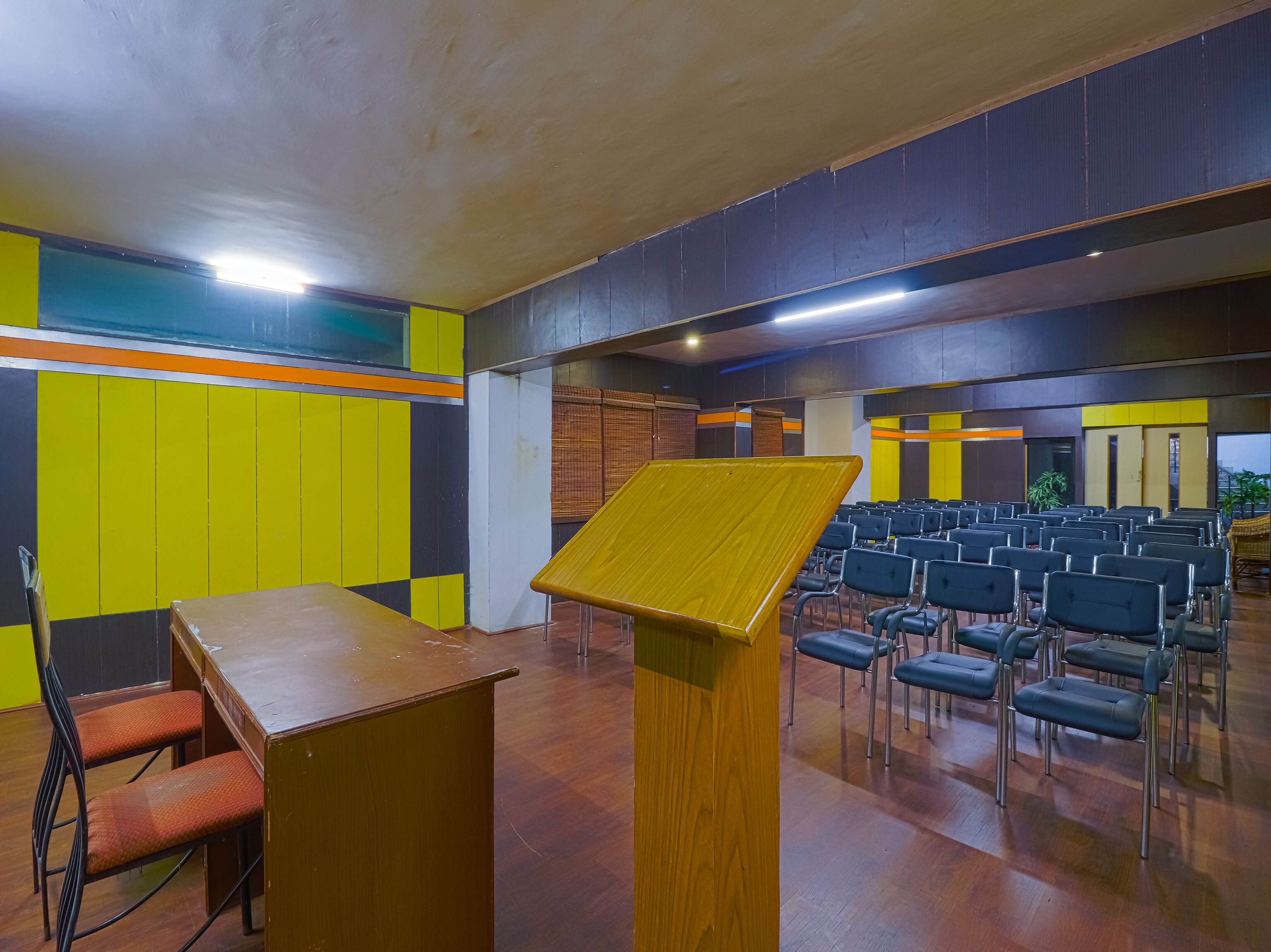 Un salón de conferencias con un atril de madera, filas de sillas y un diseño de pared colorido.