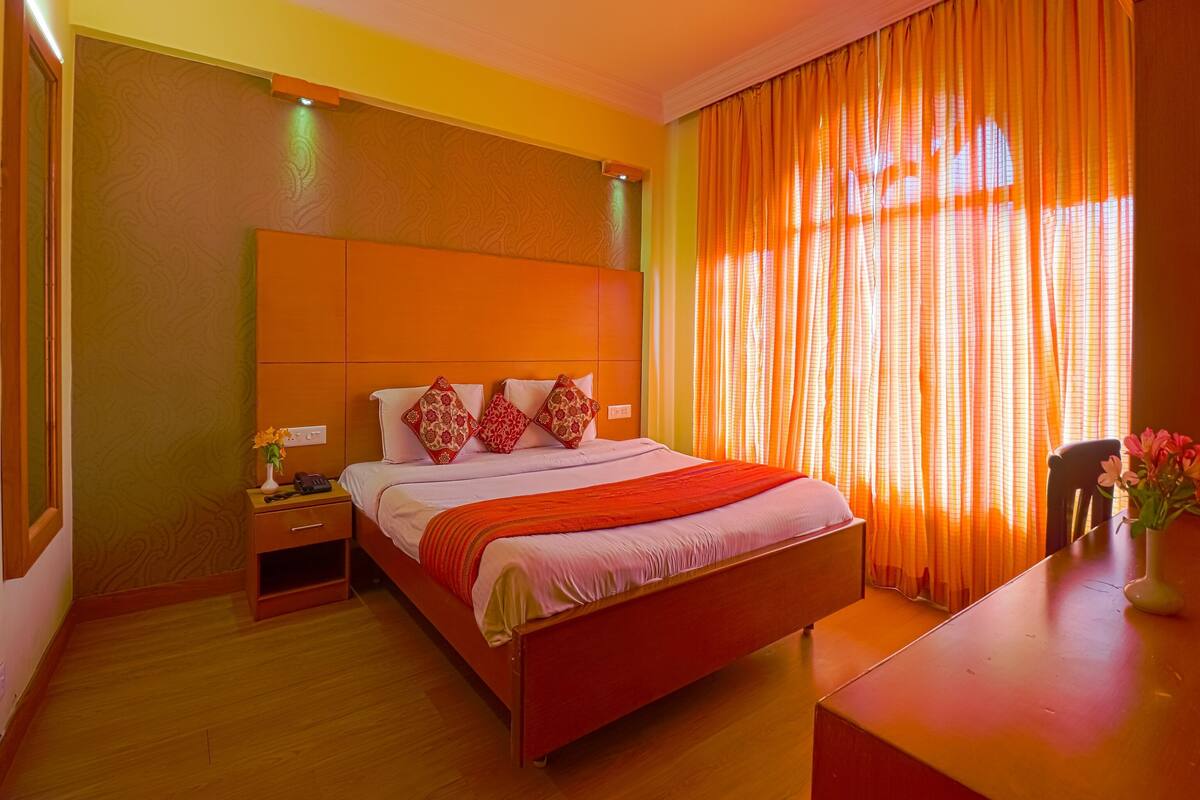 Una habitación de hotel con una cama grande, mesitas de noche y un escritorio con una silla.