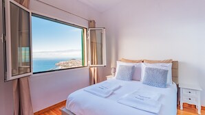 A hotel room with a large window, a bed with white linens, and a nightstand. - FLH Funchal Ocean View with Pool (Funchal)