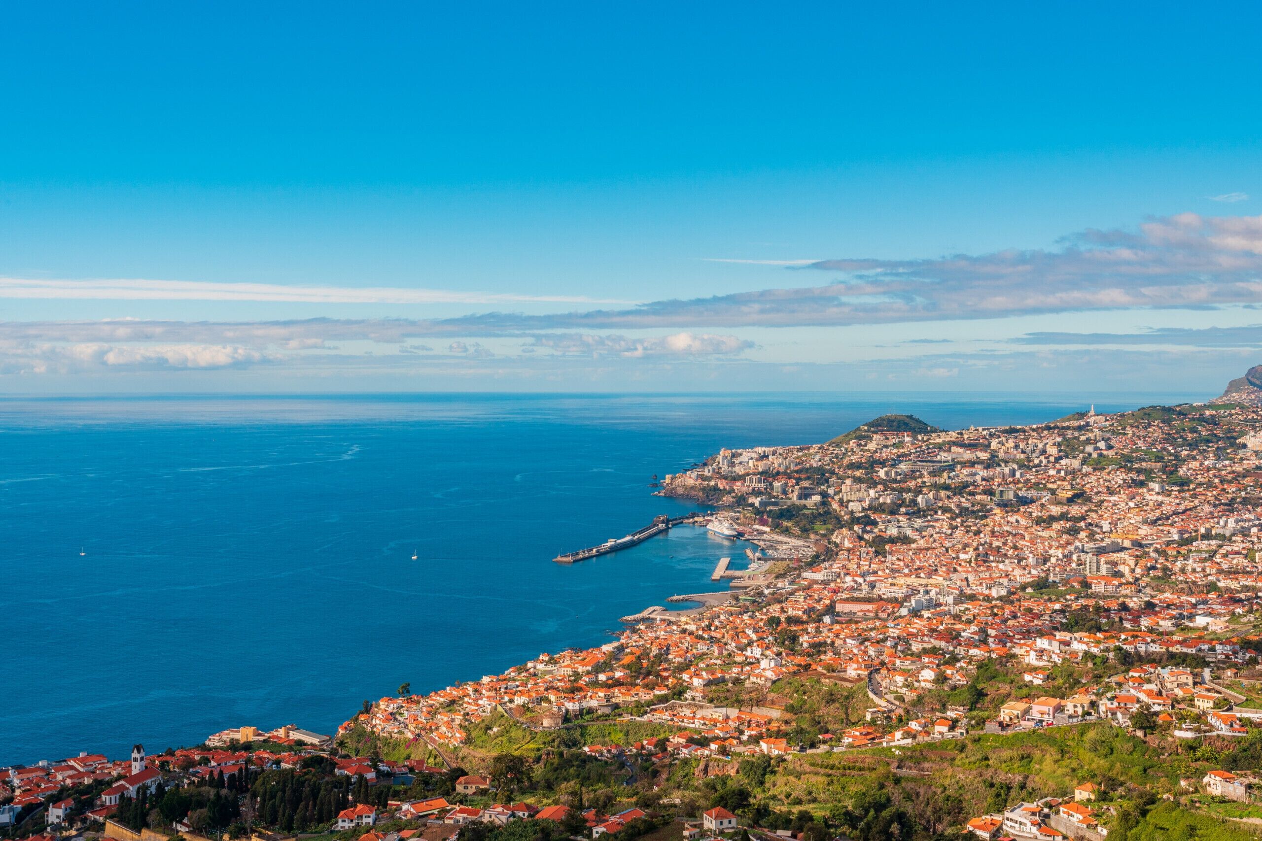A coastal town with a prominent lighthouse, dense housing, and a clear view of the sea.