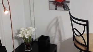 A room with a black table, a vase with white flowers, a black chair, and a wall-mounted picture of the Eiffel Tower. - Close to Carnival &  POS activities! Secure 1 bdr apt, mins from Port of Spain (St Anns)