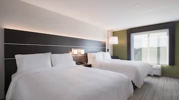 Una habitación de hotel con dos camas, una mesita de noche con lámpara, una ventana con persianas y un aplique de pared.
