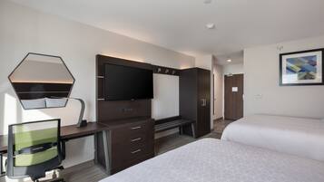 Una habitación de hotel con escritorio, una silla, una cama, un televisor y un armario.
