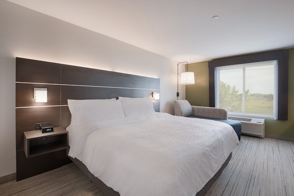 Een moderne hotelkamer met een groot bed, nachtkastjes, een lamp en een groot raam met uitzicht.