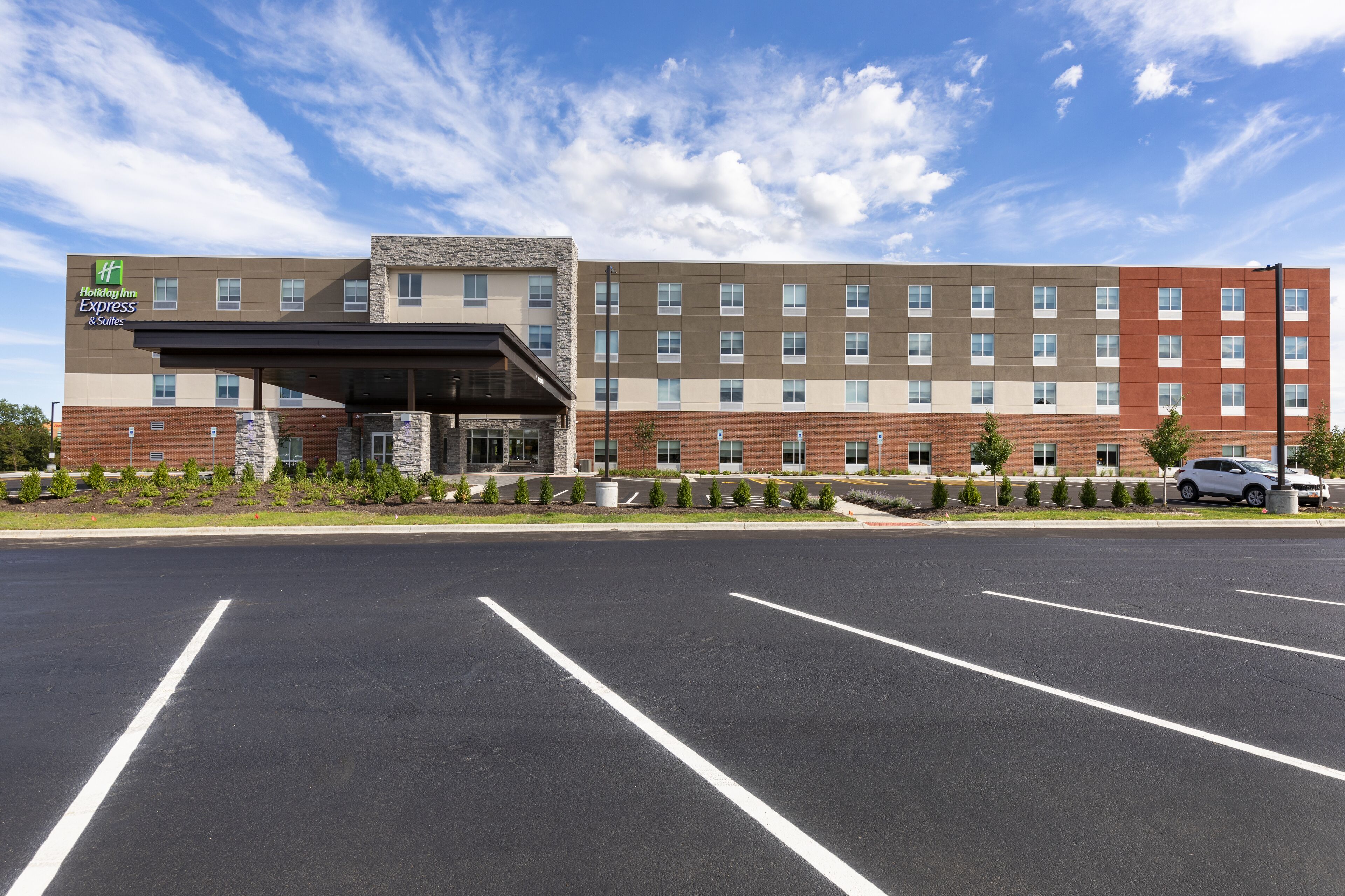 Un hôtel Holiday Inn Express doté d’une façade moderne en briques, d’une entrée abritée et d’un parking.