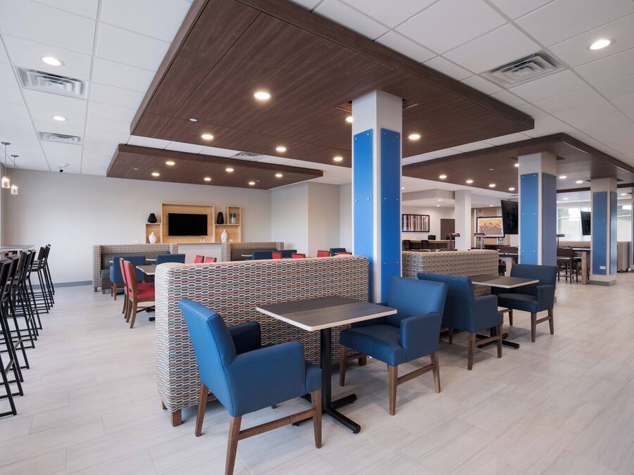 A modern restaurant with booths and tables, wooden ceiling, and recessed lighting.