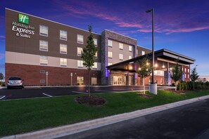 A Holiday Inn Express & Suites hotel with a brick facade, a parking lot, and a well-lit entrance. - Holiday Inn Express & Suites Chicago - Hoffman Estates by IHG (Hoffman Estates)