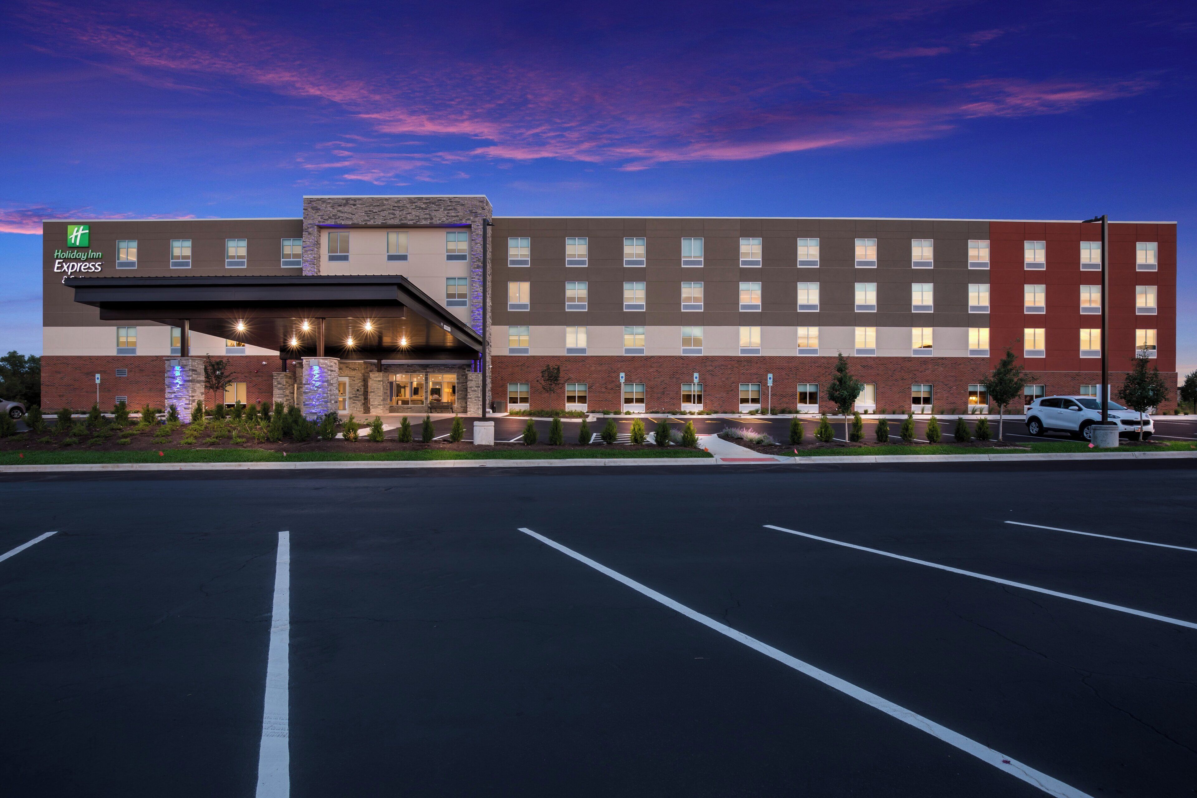 Un hotel Holiday Inn Express con un diseño moderno, destacando una fachada de ladrillo, numerosas ventanas y un estacionamiento al frente.