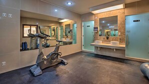 A modern bathroom with a stationary bike, large mirrors, and a vanity with a sink. - Playa del Carmen Beachfront Condo w/ Pool Access! (Playa Del Carmen)