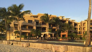 A beachfront hotel with multiple balconies, palm trees, and a pool area. - Playa del Carmen Beachfront Condo w/ Pool Access! (Playa Del Carmen)