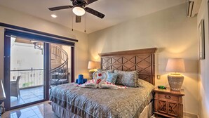 A bedroom with a bed, a ceiling fan, a nightstand, a lamp, and a view of the outside balcony. - Playa del Carmen Beachfront Condo w/ Pool Access! (Playa Del Carmen)