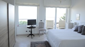 A hotel room with a large bed, a television, a chair, and a balcony with a view. - Maison Blanche Luxury B&B Taormina (Taormina)