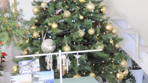 A Christmas tree with gold ornaments and lights, a glass table with papers, and a staircase in the background. - Maison Blanche Luxury B&B Taormina (Taormina)