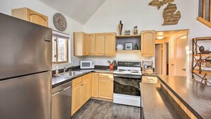 A modern kitchen with stainless steel appliances, wooden cabinets, and a microwave. - Lakes of the North Home on Snowmobile & ATV Trail! (Mancelona)