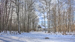 A snow-covered landscape with a house surrounded by tall trees. - Lakes of the North Home on Snowmobile & ATV Trail! (Mancelona)