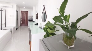 A modern kitchen with white cabinets, a glass countertop, and a hanging pot rack.