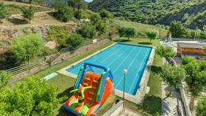 A swimming pool with a slide, surrounded by greenery and hills. - Alberg Les Estades (Rialp)