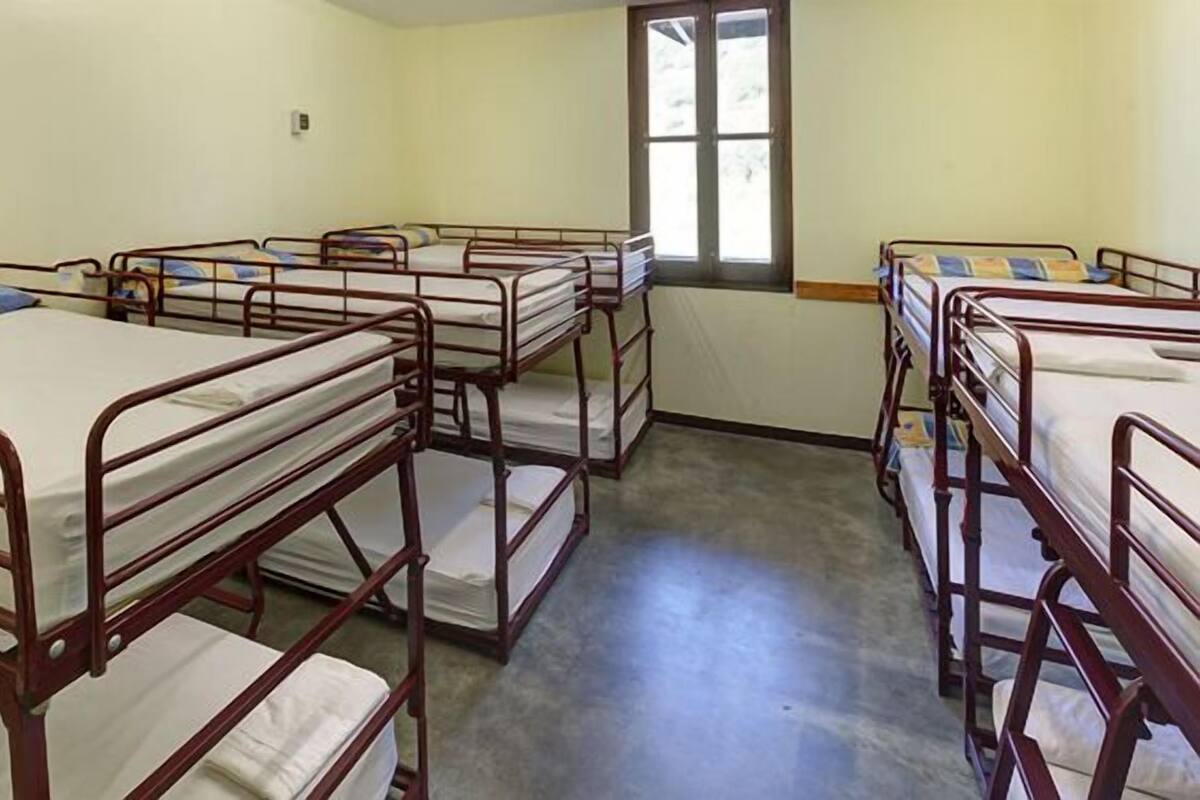 A dormitory room with bunk beds arranged in rows.