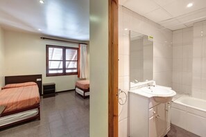 A bedroom with a bed, a window with curtains, a bedside table, and a small bedside lamp. The room has a tiled floor and a white ceiling. - Alberg Les Estades (Rialp)
