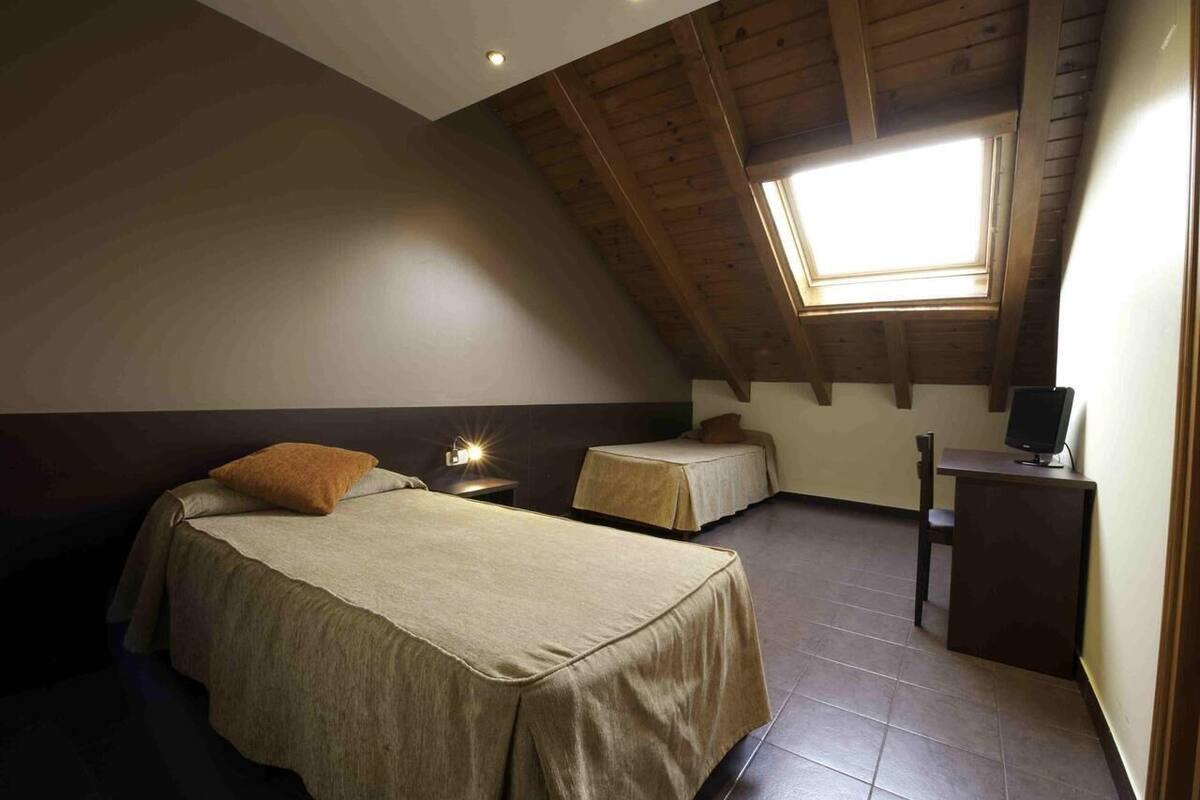 A bedroom with two beds, a desk, and a computer.