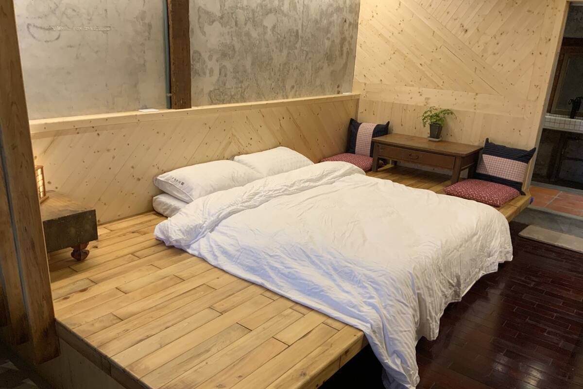 Una cama de madera con ropa blanca en una habitación con paredes y suelos de madera.