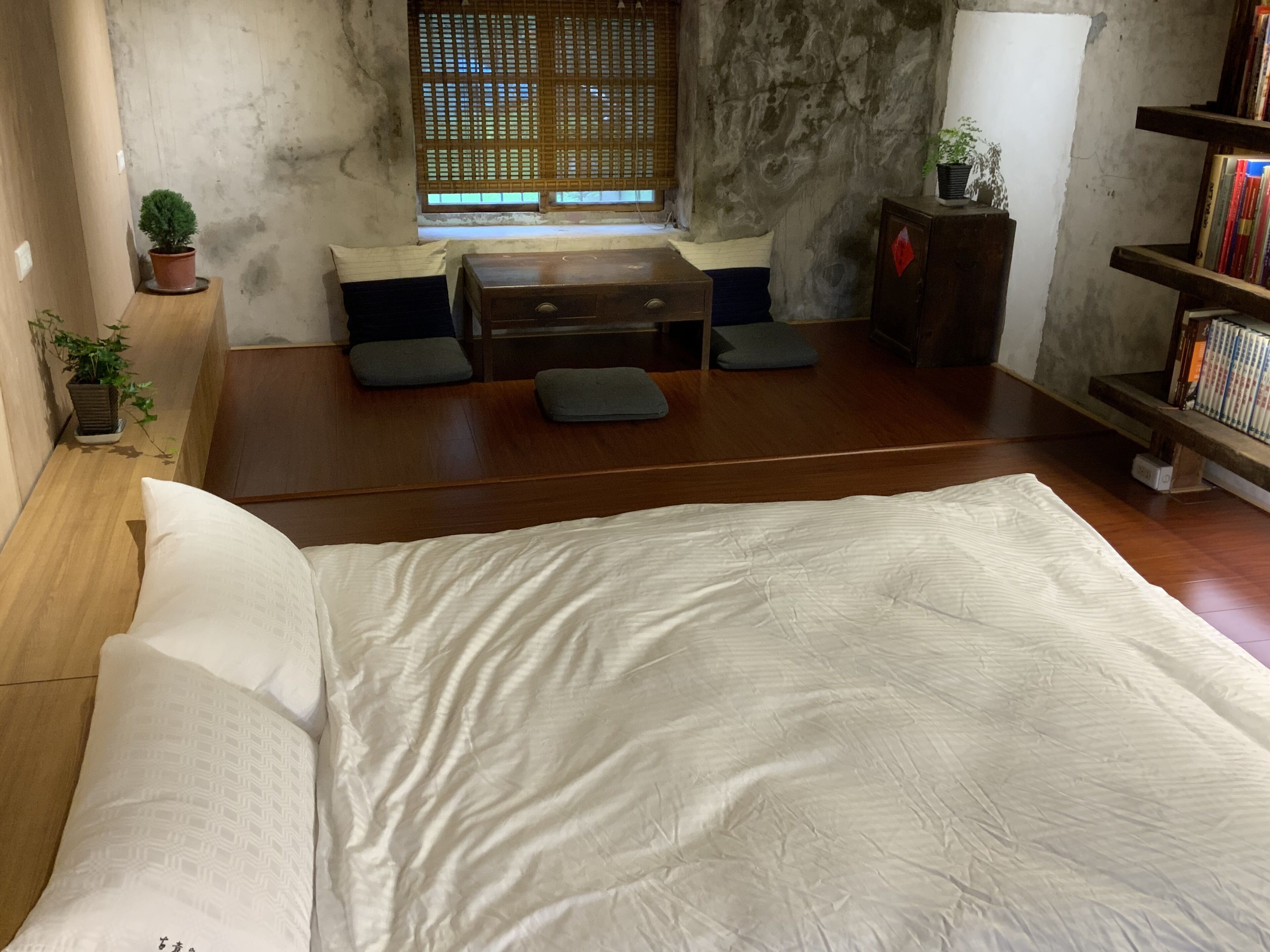 A room with a bed, a small table, and a bookshelf.