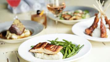A dining table with plates of food, glasses of wine, and a martini glass.