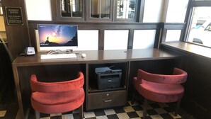 A business center desk with a computer, phone, and printer. There are two red chairs and a black and white checkered floor. - Hotel Indigo Spokane Downtown by IHG (Spokane)