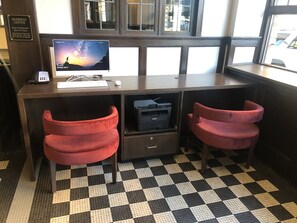 A business center desk with a computer, phone, and printer. There are two red chairs and a black and white checkered floor. - Hotel Indigo Spokane Downtown by IHG (Spokane)