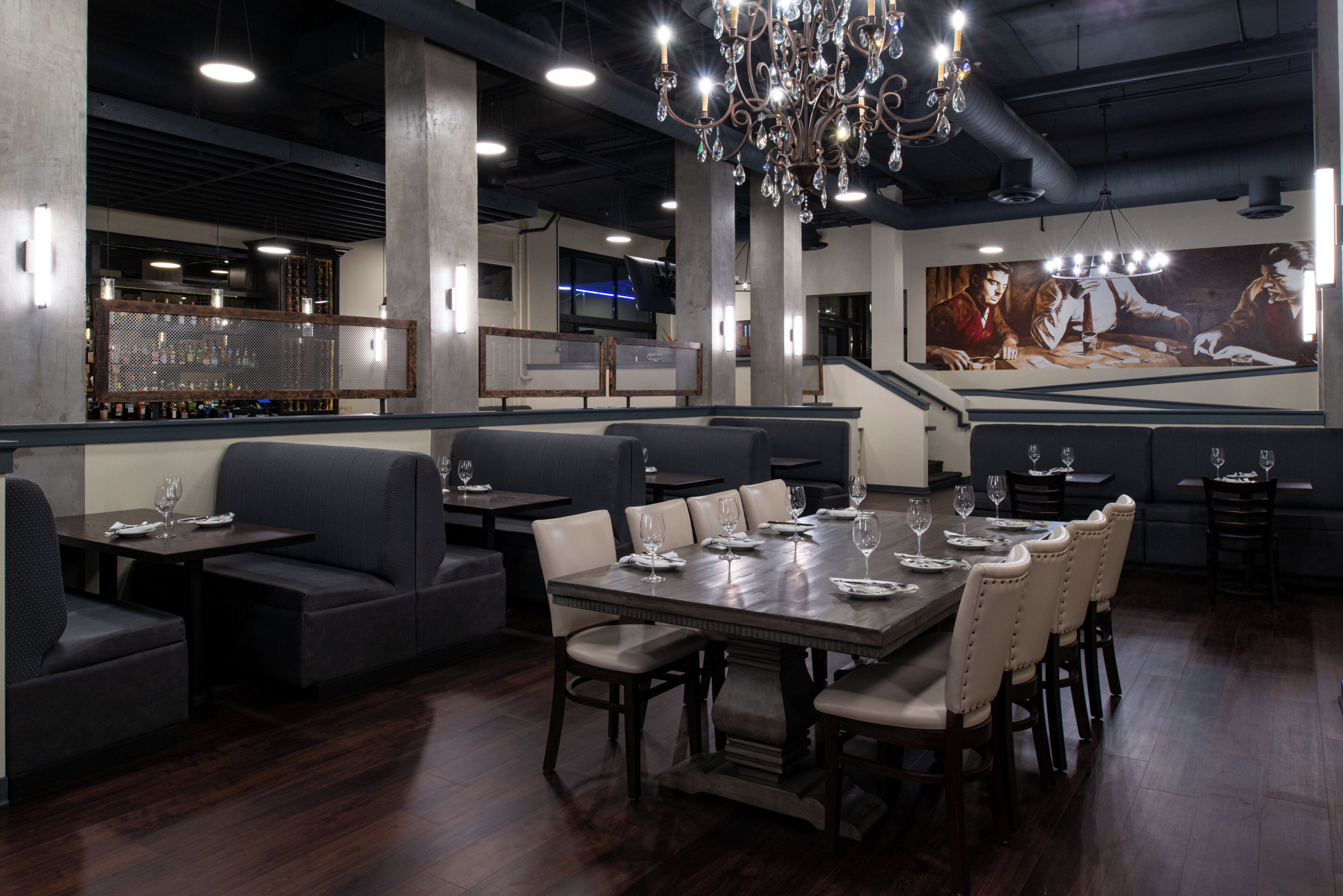 A restaurant interior with a long dining table, booths, and a bar area.