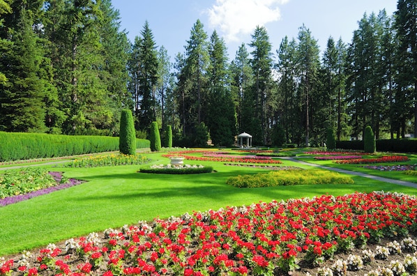 A formal garden with manicured lawns, flower beds, and a gazebo.