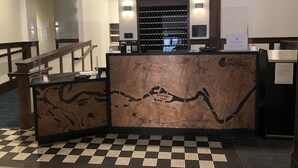 A reception desk with a map design, a staircase, and a check-in counter. - Hotel Indigo Spokane Downtown by IHG (Spokane)