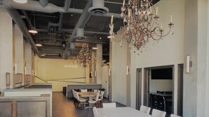 A modern dining area with a long white table, cushioned seating, and a chandelier. - Hotel Indigo Spokane Downtown by IHG (Spokane)