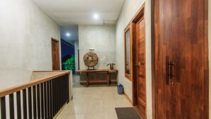 A hallway with a wooden bench, a small table with a potted plant, and a wooden door. - Kuta Legian Villa (Kuta)
