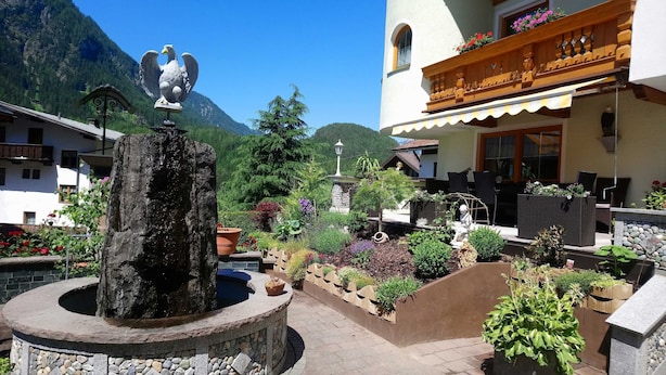 Un cortile con una fontana in pietra, una statua e un edificio con un balcone.