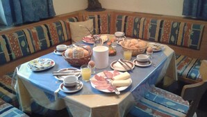Una tavola imbandita per la colazione, circondata da sedute imbottite con motivi decorativi.