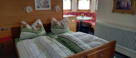 Un letto con biancheria da letto a motivi floreali, una testata in legno e un comodino con un vaso.