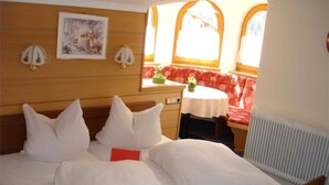 Una camera d'albergo con un letto, un tavolino, una panca e un termosifone.
