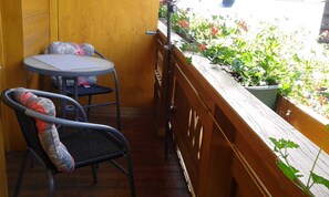 Un balcon avec une balustrade en bois, une petite table et une chaise.