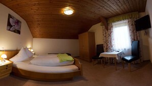 Ein Schlafzimmer mit einem runden Bett, einem Schreibtisch, einem Sessel, einem Fernseher und einem Kleiderschrank.