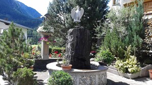 Um jardim com uma fonte, uma estátua e diversas plantas.