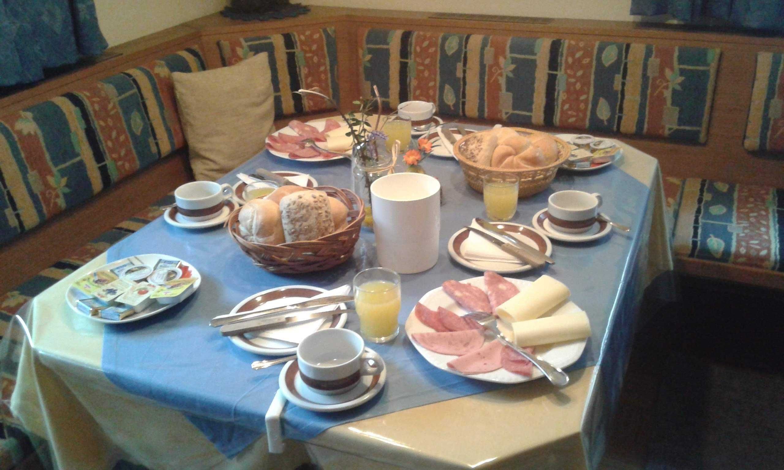Ein Frühstückstisch ist gedeckt mit Tellern, Brot, Butter und Saft.